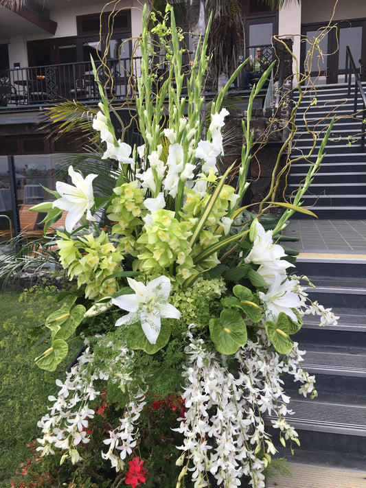 This gorgeous wedding entrance piece consists of white gladiolas high and to the back with green Cymbidium orchids and white Casablanca lilies towards the middle, green Anthurium towards the bottom and lovely white orchids cascading towards the bottom, a beautiful statement piece. 