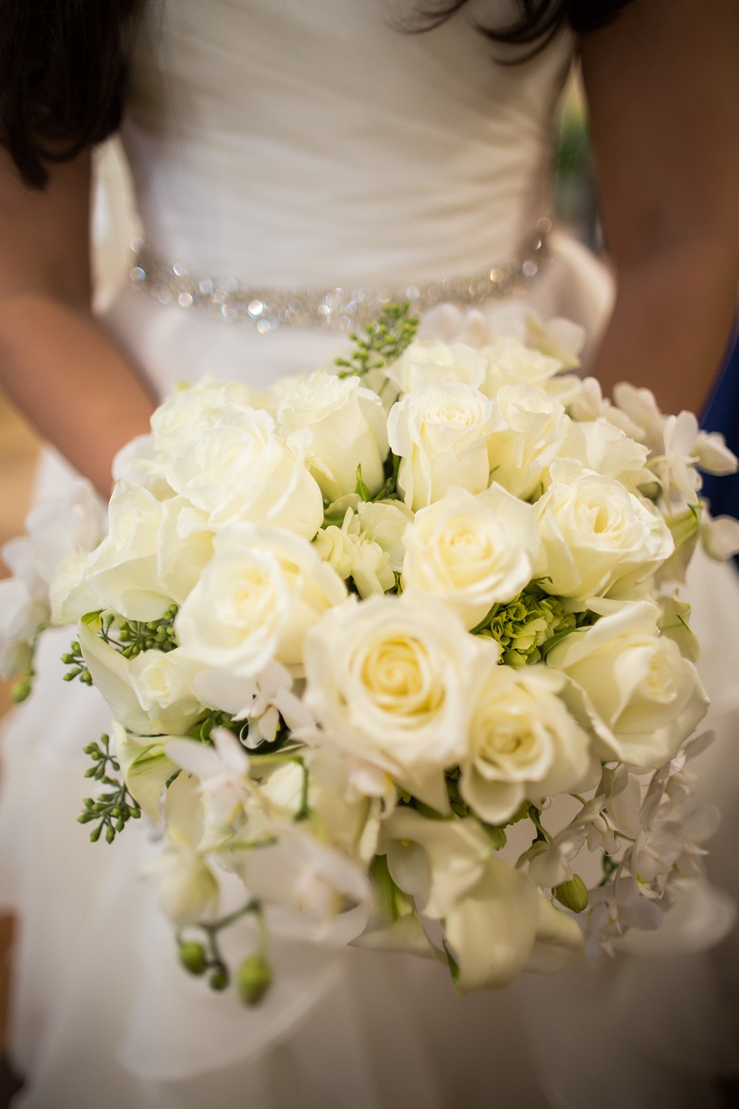 The gorgeous white bouquet includes white roes along with white orchids accompanied by seeded eucalyptus. 